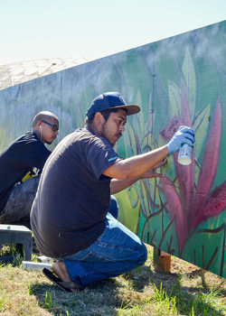 two artists spray painting a mural