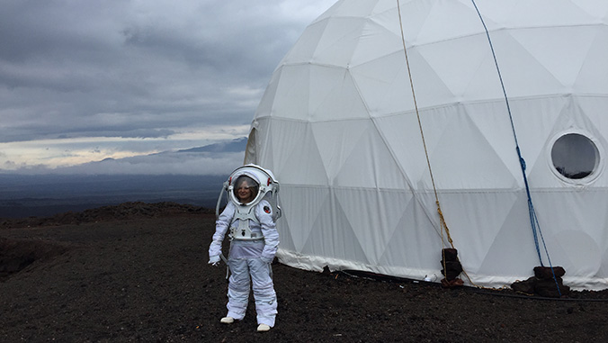 Researcher in space suit in front of HI SEAS dome