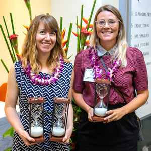 2 students holding hourglass trophy