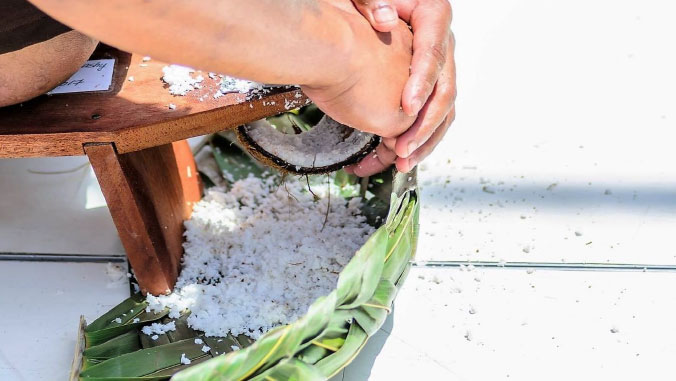 Photo of hands scraping a coconut.