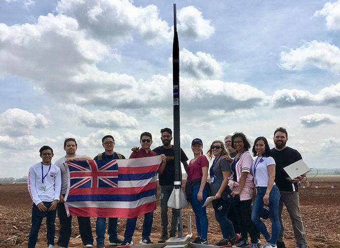 Team posing with rocket and Hawaii flag