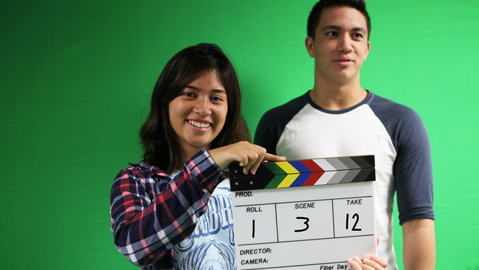 girl holding clapper board, guy standing beside her