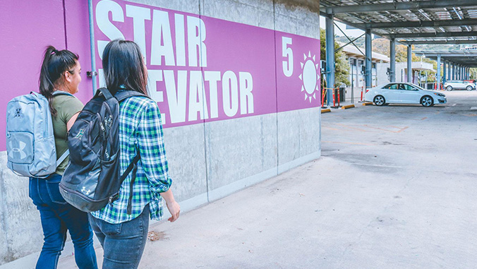 Students walking next to a large sign indicating stairs and elevator