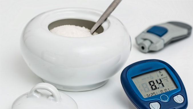 Bowl of sugar with diabetes monitoring instruments