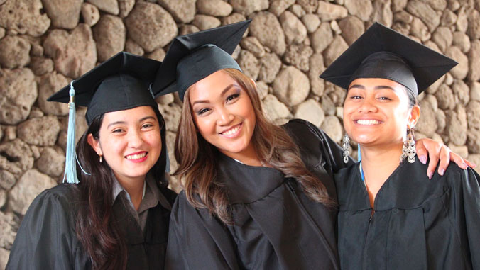 3 community college graduates in cap and gown