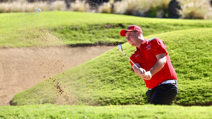 man hitting golf ball out of sand