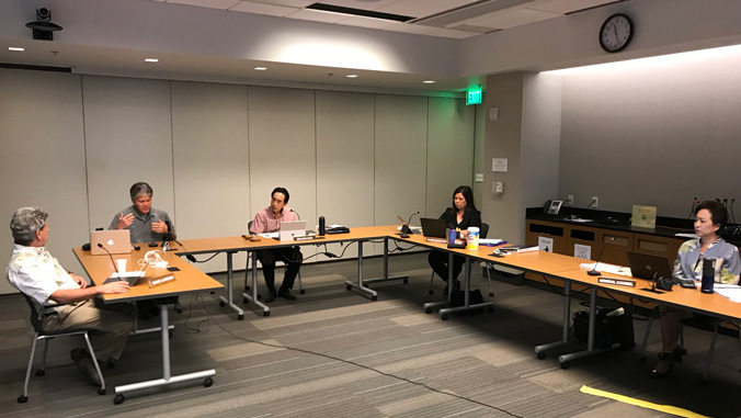 People sitting six feet apart in a conference room