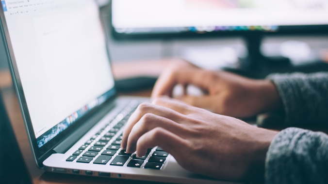 two hands typing on keyboard