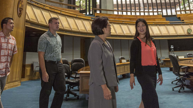 four people walk through State Capitol chambers