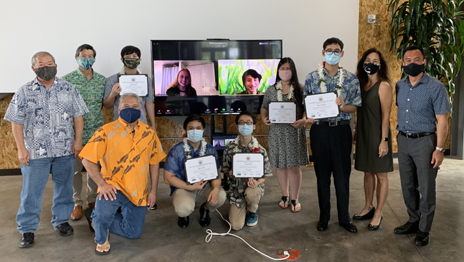 people pose for camera holding up certificates