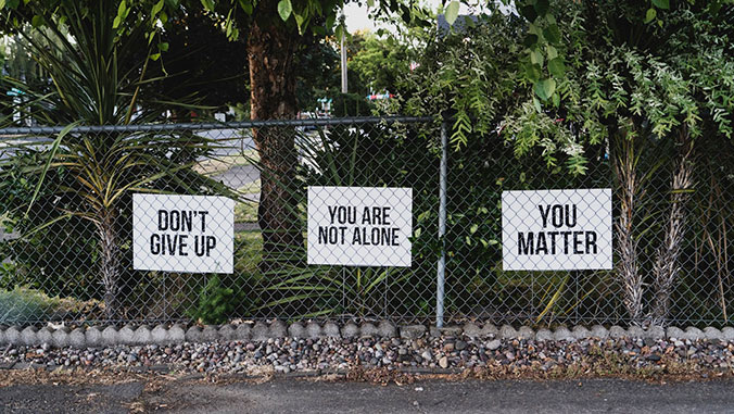 signs on a fence saying you are not alone