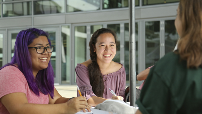 three people sitting on a table smiling