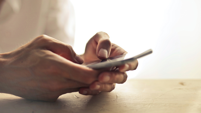 two hands typing on a phone