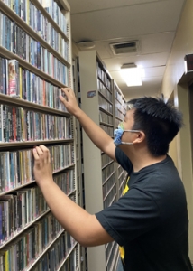 person looking up records on a shelf