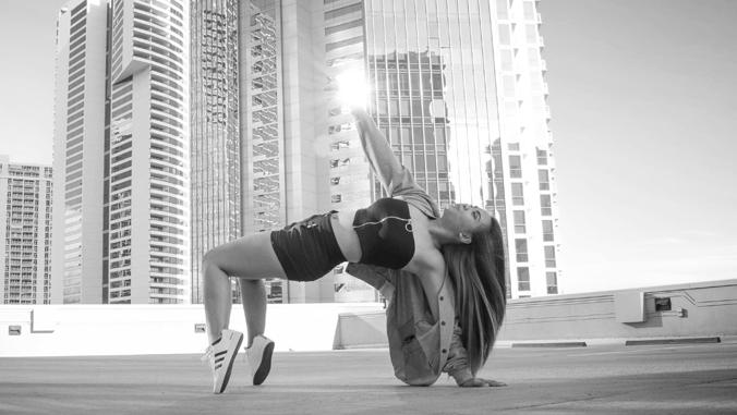 person performing a dance move with buildings in the background