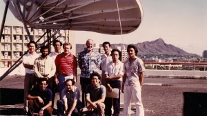 people standing next to a satellite with Diamond Head in the background