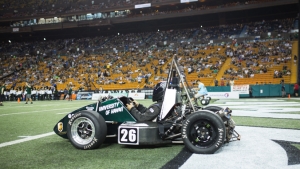 car on aloha stadium field with hundreds of people in the stands