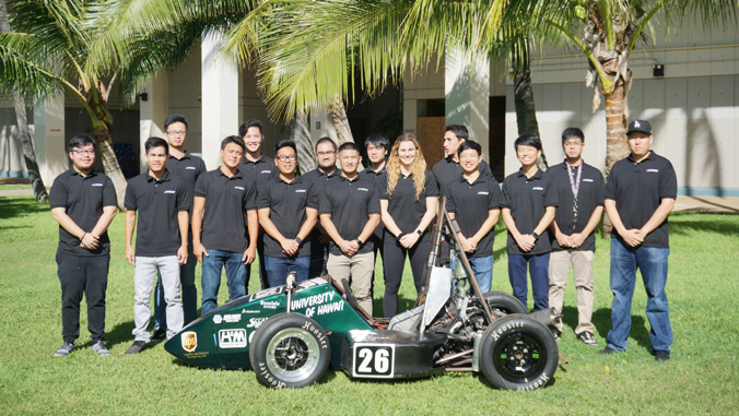 people standing smiling at camera next to green racing car