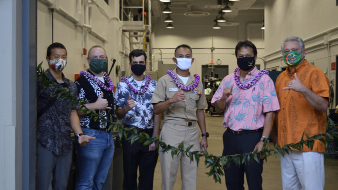 six people posing for camera with a maile lei
