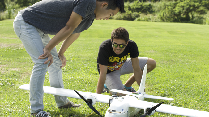 two people standing over a drone plane
