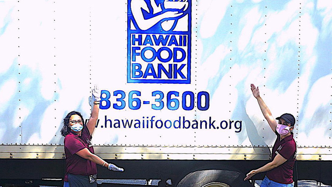 Two volunteers standing in front of a Foodbank truck