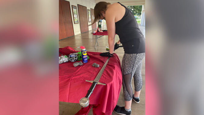 person using a wire brush to scrub the top of a sword