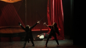 two people fighting with swords on a stage