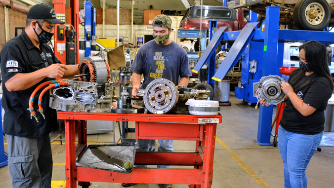 3 people working on a car engine