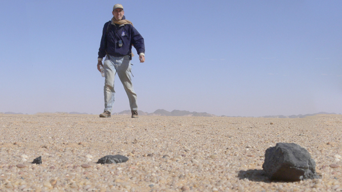 person looking at meteorite