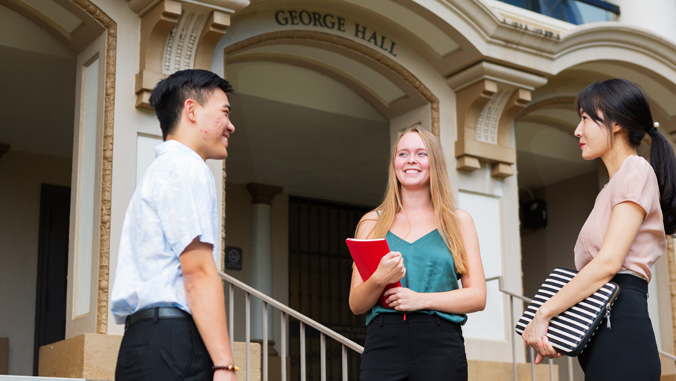 three people smiling in front of a building