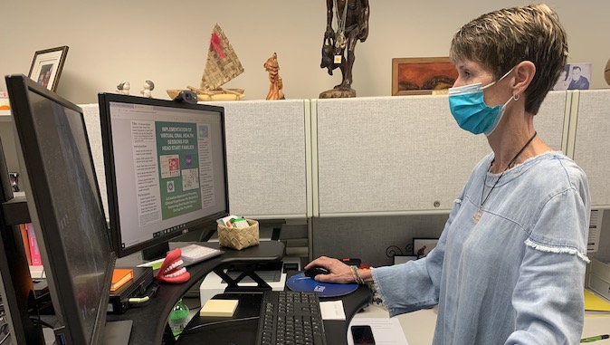 female with mask looking at computer screen