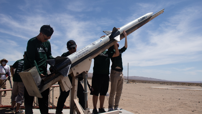 people standing prepping a rocket to launch