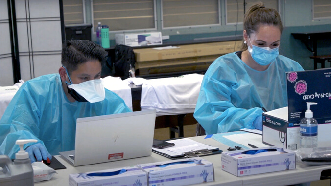 people in protective gear sitting in front of a computer