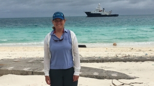 person smiling at camera with a boat in the background