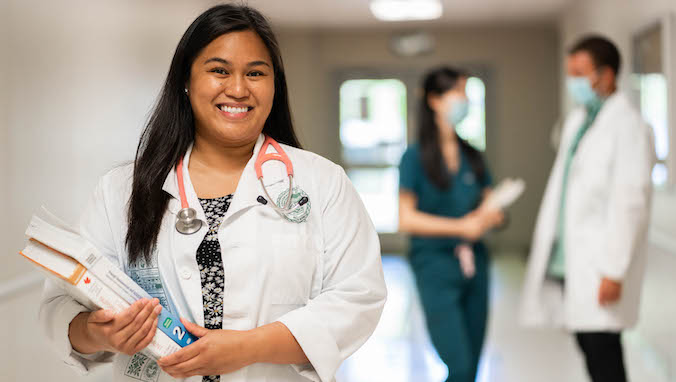 student nurse smiling with 2 people in background