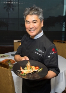 chef holding a plate of food and smiling at camera
