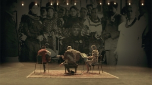 three people sitting down on a chair facing other way