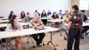 standing person talking to several people sitting with desks