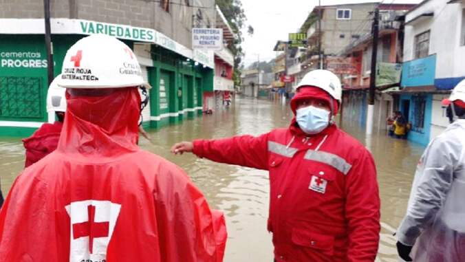 men wearing Red Cross vest in flooded street