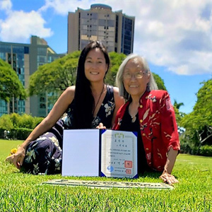 Mother and daughter with a certificate in front of a grave