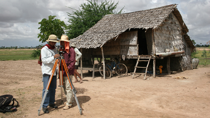 people looking at a device next to a small house