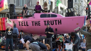 people around a pink boat with "Tell the truth"