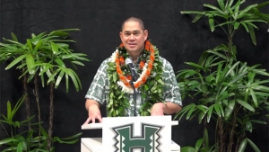 person with lei standing at a podium