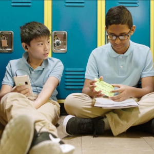 two boys sitting in front of lockers