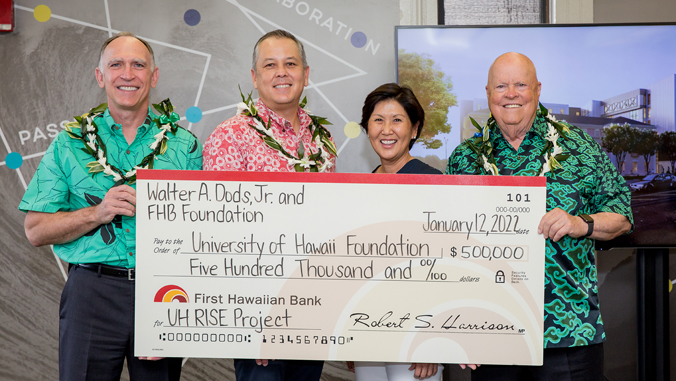 four people standing with a check