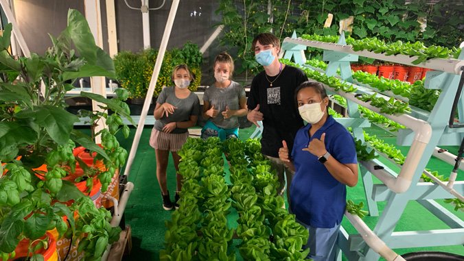 Students flashing shaka with vegetables