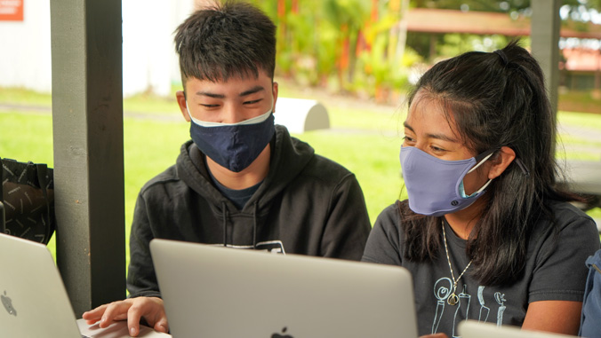 Two students in masks at laptops