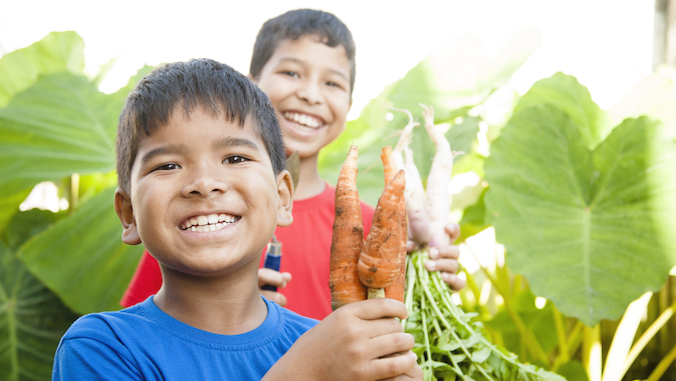 two boys holding up carrots