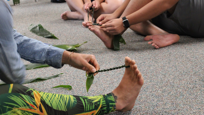 People making lei using their feet