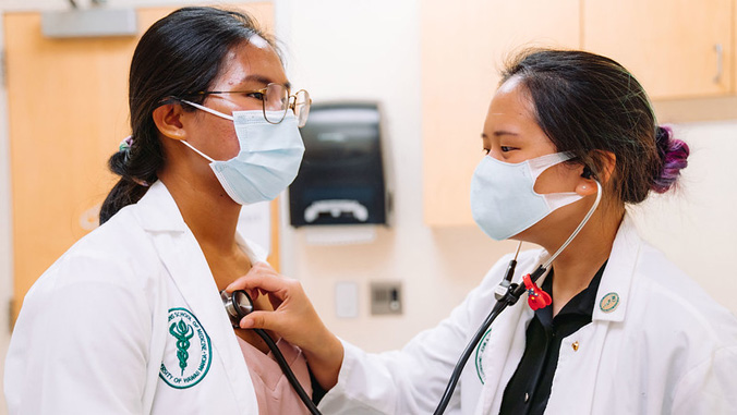 Two medical students using a stethescope